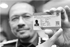  ?? Bernama photo ?? File photo shows Immigratio­n Department director-general Datuk Seri Mustafar Ali showing the E-Kad for the foreign illegal workers earlier this year.