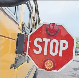  ??  ?? A school bus with its stop sign out and lights flashing.