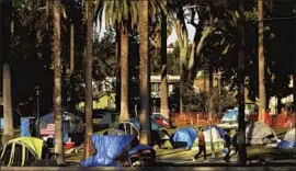  ?? Genaro Molina Los Angeles Times ?? PARKGOERS walk past a homeless encampment in Echo Park last month before it was cleared by the city. The large camp became a commune-like community.