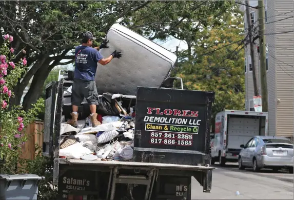  ?? NANCY LANE — BOSTON HERALD ?? Workers toss a mattress during student move-in day in Allston in 2022.