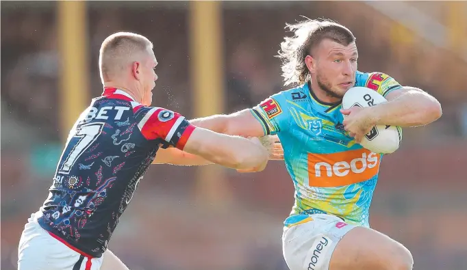  ??  ?? Titans forward Jai Arrow puts a fend on Roosters halfback Kyle Flanagan. He has no regrets about leaving the club to join the Rabbitohs next season. Picture: Getty Images