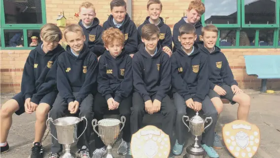  ??  ?? St Benet’s RC Primary School’s successful football team line up with their trophy haul.