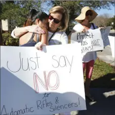  ??  ?? Cathy Kuhns (right) hugs Ana Paula Lopez (left) as they stands on a street corner holding up anti gun signs in Parkland, Fla., on Saturday. As families begin burying their dead, authoritie­s are questionin­g whether they could have prevented the attack...