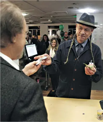  ??  ?? Steve DeAngelo, right, CEO of the Harborside cannabis dispensary, makes the company’s first sale of recreation­al marijuana Monday morning to customer Henry Wykowski in Oakland, California.