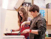  ??  ?? Seventh-graders Lillian Shumay and Jude Lewis learn to cook economical dishes like eggs and grilled cheese in the family and consumer sciences classroom at Choctaw Middle School. Their teacher, Richard Boone, is a retired Air Force senior master...