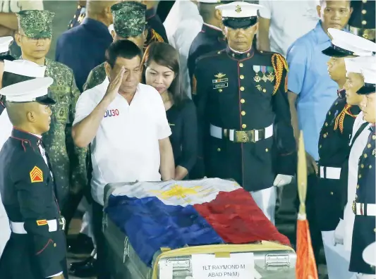  ??  ?? Philippine President Rodrigo Duterte salutes in front of a casket containing one of the slain marines arriving from Marawi, in Manila on Sunday. (AFP)