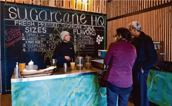  ?? Photos by Don Feria/Special to The Chronicle ?? A.T. Nguyen talks with customers at Sugarcane HQ in San Bruno, a new shop devoted to fresh sugarcane juice, which is becoming popular in the Bay Area.