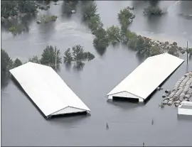  ?? STEVE HELBER — THE ASSOCIATED PRESS ?? Hog farm buildings are inundated with floodwater from Hurricane Florence near Trenton, N.C., Sunday.