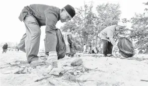  ??  ?? WAN Sukairi (kanan) turut sama turun padang mengutip sampah sarap yang ditinggalk­an oleh segelintir pengunjung yang beriadah pada waktu petang ketika tinjauan di Pantai Kuala Ibai.