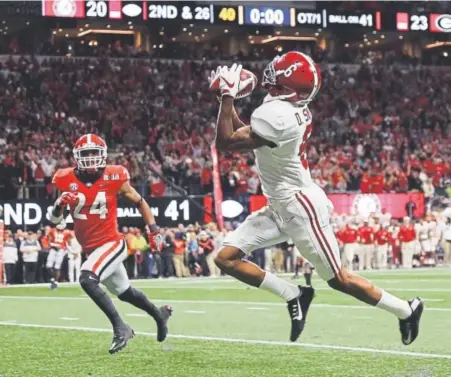  ?? Mike Ehrmann, Getty Images ?? Alabama’s DeVonta Smith hauls in the winning 41-yard touchdown pass from freshman quarterbac­k Tua Tagovailoa in overtime Monday night to beat Georgia and safety Dominick Sanders 26-23 at Mercedes-Benz Stadium in Atlanta.