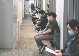  ?? NATHAN DENETTE / THE CANADIAN PRESS ?? Frontline workers at Apotex in Toronto prepare for their COVID-19 vaccinatio­ns last week. A new federal policy will grant permanent status to 90,000 essential workers.