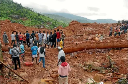  ?? PHOTO: REUTERS ?? Residents watch as rescue workers search for survivors after a mudslide in the mountain town of Regent, Sierra Leone.