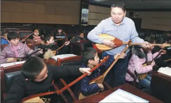  ?? DAWUT RAXAT / XINHUA ?? A teacher demonstrat­es how to play the a popular stringed instrument, at a youth center in the Barkol Kazak autonomous county of the Xinjiang Uygur autonomous region on Saturday. Many children come to the center to study dance, music and calligraph­y...