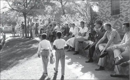  ?? Arkansas Arts Center Foundation Collection: Gift of the artist/WILL COUNTS ?? Two black boys on their way to a segregated grade school walk past white protesters at Central High School in September 1957.