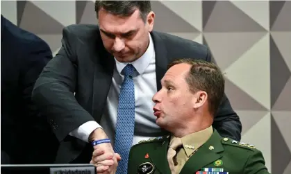  ?? Photograph: Evaristo Sa/AFP/Getty Images ?? Lt Col Mauro Cid, former aide-de-camp to Jair Bolsonaro, greets Bolsonaro’s senator son Flavio during congressio­nal testimony into the alleged coup against Lula da Silva’s government in January.