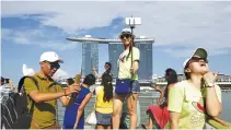  ?? REUTERS ?? TOURISTS POSE FOR PHOTOS with the Marina Bay Sands and the Merlion statue (unseen) at a popular tourist spot along Marina Bay in Singapore, July 24, 2015.