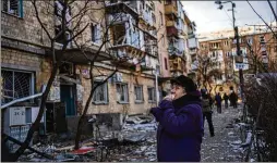  ?? RODRIGO ABD/ASSOCIATED PRESS ?? A woman looks at residentia­l buildings damaged by a bomb in Kyiv, Ukraine, on Friday. Russian forces pressed their assault on cities Friday, with new strikes and shelling on the edges of the Kyiv and the western city of Lviv.