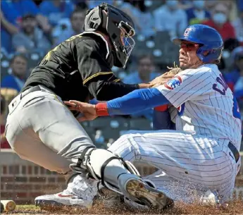  ?? Matt Freed/Post-Gazette ?? Jacob Stallings, right, tags out Willson Contreras at the plate in the fifth inning Saturday Wrigley Field in Chicago. at