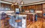  ??  ?? The kitchen has gorgeous wood cabinetry, natural stone counters and stainless-steel appliances.