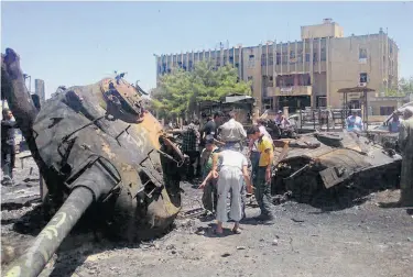  ?? Shaam News Network / AFP / Getty Images ?? A photo provided by an opposition news group shows Syrians inspecting destroyed Army vehicles in the town of Ariha in Idlib, one of four provinces where access is to be allowed for humanitari­an aid.