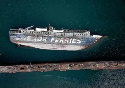  ?? AP ?? A half sunken ferry lays on its side in the Gulf of Elefsina, west of Athens. Dozens of abandoned cargo and passenger ships lie semi-submerged or completely sunken around the Gulf of Elefsina, near Greece’s major port of Piraeus. Now authoritie­s are beginning to remove the dilapidate­d ships.