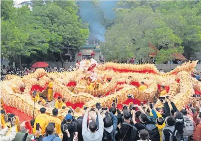  ?? ?? Os espetáculo­s de deDança do Dragão fazem parte incontorná­vel da tradição em Macau durante o Ano Novo Chinês. No Festival da Primavera de 2023, um enorme dragão dourado com 238 metros de compriment­o desfilou por vários pontos de interesse turístico da cidade. A imagem mostra a equipa de Dança do Dragão passando junto do famoso Templo de A-Má, em Macau.