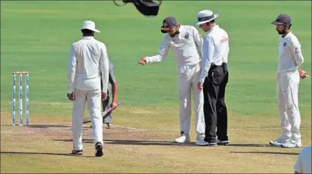  ?? AFP ?? Skipper Virat Kohli (centre) points out marks on the pitch to onfield umpire Richard Kettleboro­ugh during the third day of the Pune Test. India lost the Test by 333 runs,