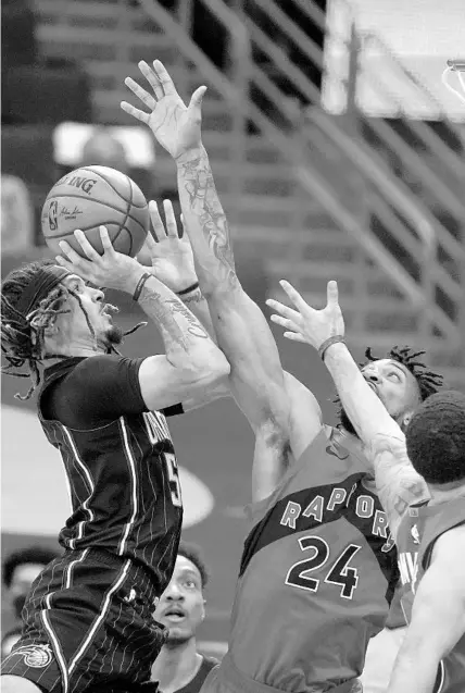  ?? CHRIS O’MEARA/AP ?? Magic guard Cole Anthony shoots over Toronto Raptors center Khem Birch, center, and guard Fred VanVleet during the second half Friday night in Tampa.