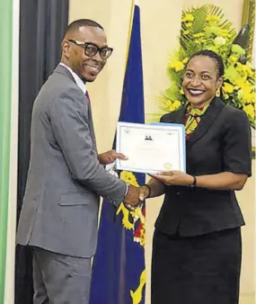  ?? ?? Mark Davis collects his scholarshi­p certificat­e from state minister in the Ministry of Finance and the Public Service Marsha Smith.