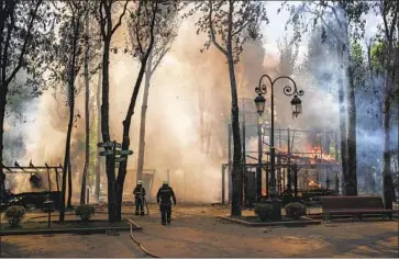  ?? Felipe Dana Associated Press ?? UKRAINE has pushed Moscow’s forces back from the city of Kharkiv to fewer than a dozen miles from the Russian border. Above, firefighte­rs douse flames at a Kharkiv park after a recent Russian bombardmen­t.