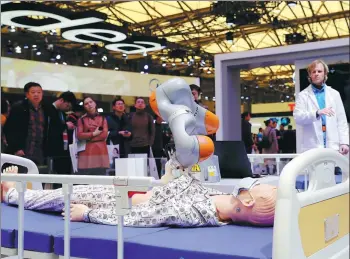  ?? FANG ZHE / XINHUA ?? Visitors watch a medical robot designed by KUKA at the Appliance and Electronic­s World Expo in Shanghai on Thursday.