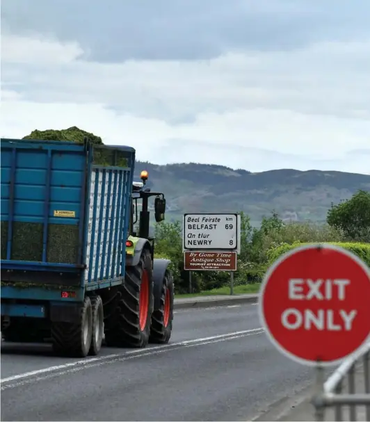  ?? ?? ► Un tractor pasa junto a una señal de salida y una de tráfico de Belfast en la frontera entre Irlanda del Norte e Irlanda.