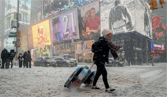  ?? AP ?? New Zealander Rebecca Hollis struggles through appalling weather in Times Square, New York this week. Vast areas of the US have been struck by a massive winter storm that has brought snow along the coast, strong winds and what could be record-low...