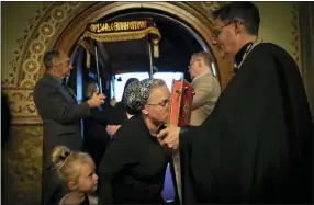  ?? ?? A little girl watches as her mother kisses the Gospel book as she enters the church Friday during a Good Friday service at St. Mary’s Ukrainian Orthodox Cathedral in Allentown, Pa..