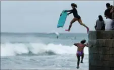  ?? JOHN LOCHER — THE ASSOCIATED PRESS ?? Bodyboarde­rs jump into the surf along Waikiki Beach ahead of Hurricane Lane, Friday in Honolulu.