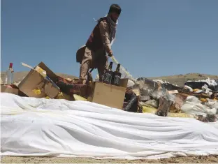  ?? (Omar Sobhani/Reuters) ?? AN AFGHAN worker prepares to burn a pile of illegal drugs and alcohol in the outskirts of Kabul yesterday.