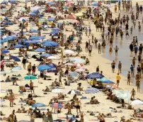  ?? AFP ?? Beachgoers sit and walk in the water at Sydney’s Bondi Beach on a hot summer day in Australia. —