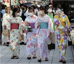  ?? /Reuters ?? Heatwave: Women wearing summer kimonos use portable fans as they walk on the street in the Asakusa district in Tokyo on Wednesday. The Japanese government issued a warning over a possible power crunch as temperatur­es soared towards 40°C in Tokyo on the fifth day of the capital’s worst June heatwave since records began in 1875.