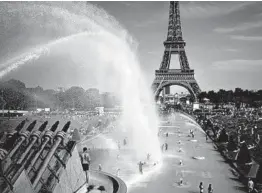  ?? LEWIS JOLY/AP ?? People cool off June 28 in front of the Eiffel Tower in Paris. On Thursday, it was announced that last month was the hottest June with records dating back to 1880.