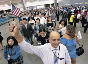  ?? Luis Sinco Los Angeles Times ?? NEW ARRIVALS to the U.S. are increasing­ly better educated and well off. Above, a U.S. Citizenshi­p and Immigratio­n Services assistant leads new citizens into the L.A. Convention Center for a naturaliza­tion ceremony.