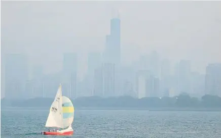  ?? TRENT SPRAGUE/CHICAGO TRIBUNE ?? A sailboat passes Montrose Point in front of a hazy Chicago skyline on July 26.