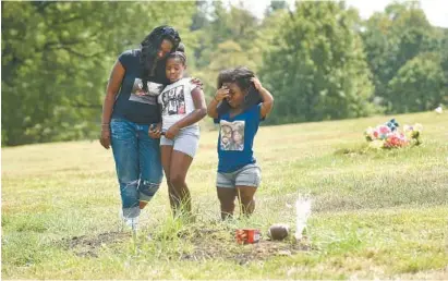  ?? LLOYD FOX/BALTIMORE SUN ?? Robin Johnson visits the grave of her son, Josh Remus Burnett, at the Arbutus Memorial Park Cemetery. Josh, 15, was fatally stabbed by a 13-year-old during a dispute. Johnson is accompanie­d by her daughters, Ja’mya Robinson, 8, and Jasmine Wells, 22,...