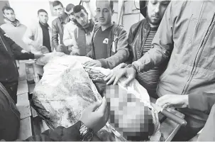  ?? — Gambar AFP ?? SYAHID: Saudara-mara yang sedih mengerumun­i jenazah Hijaila di rumah mayat di hospital al-Shifa di Semenanjun­g Gaza semalam.