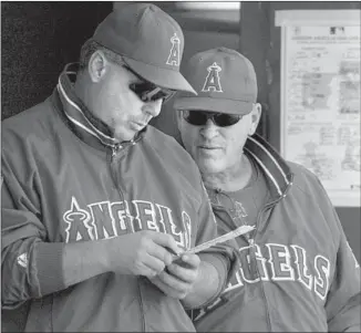  ?? Christine Cotter Los Angeles Times ?? JOE MADDON, right, then the Angels’ bench coach, looks over a lineup card with manager Mike Scioscia during the final game of the 2004 regular season. Maddon is the new Angels manager.