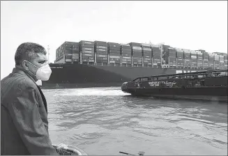  ?? AP ?? An official from the Suez Canal Authority investigat­es the scene where the Ever Given, a cargo ship, got wedged across the Suez Canal, blocking traffic in the vital waterway.