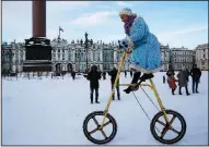  ?? AP/DMITRI LOVETSKY ?? A woman wearing a Snow Maiden costume rides a bike Sunday during a celebratio­n of Old New Year at the Palace Square in St. Petersburg, Russia. Many people in Russia observe the occasion, which marks the changing of the year under the Julian calendar.