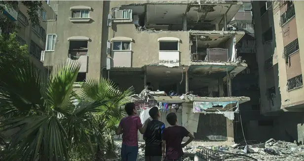  ?? AP ?? Vecinos de Ciudad de Gaza observan el balance de daños del bombardeo israelí en el que falleciero­n diez miembros de la familia Abu Hatab Habibi, ayer