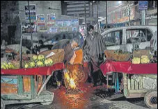  ?? AP ?? Kashmiri street vendors try to keep themselves warm on a cold Wednesday evening.