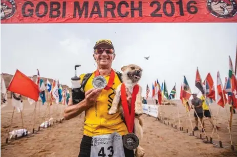  ?? 4DESERTS PHOTOS ?? Dion Leonard, who won second place in the Gobi March 2016, holds the dog who ran alongside him throughout the gruelling seven-day ultra-marathon.
