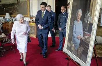  ?? STEVE PARSONS/PA ?? The Queen accompanie­d by (from left) artist Stuart Brown, Air Commodore Scott Miller, Deputy Commandant of The Defence Academy of the United Kingdom, Warrant Officer Shaun Griffin and Wing Commander Dale White, RAF Force Protection Force, as she views a new portrait of her at Windsor Castle